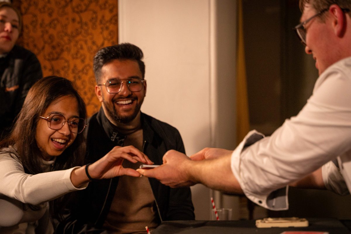 An audience member laughing in amazement as a magician performs an astonishing card trick right in their hands